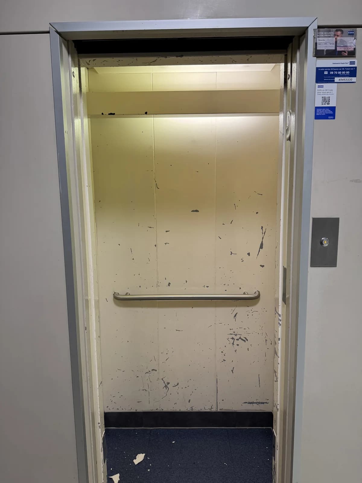 Avant : Paroi claire et marquée d’une cabine d’ascenseur, photographiée depuis le palier avant rénovation.